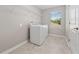 Bright laundry room featuring modern appliances, a window, and practical wire shelving for storage at 3038 Camden Way, Davenport, FL 33837