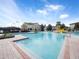 Community pool with zero entry, mushroom fountain, and water slide surrounded by lush landscaping at 3038 Camden Way, Davenport, FL 33837