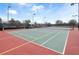 Well-maintained community tennis courts featuring green and red surface, surrounded by fencing and lush greenery at 3038 Camden Way, Davenport, FL 33837