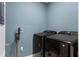 Laundry room features a dark washer and dryer, blue walls, and a mounted stick vacuum on the wall at 3161 Royal Tern Dr, Winter Haven, FL 33881