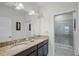 Bathroom with double sink vanity, granite countertop, a large mirror, and a glass-enclosed shower at 510 Captiva Dr, Davenport, FL 33896