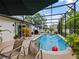 Inviting pool area features loungers, lush tropical plants, and a large umbrella for shade at 572 Nogales Ct, Kissimmee, FL 34758