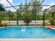 Enclosed pool area featuring a clear blue pool, lush greenery, and a well-maintained patio at 572 Nogales Ct, Kissimmee, FL 34758