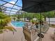Covered patio featuring a pool with a water feature, surrounded by manicured plants and comfortable seating at 572 Nogales Ct, Kissimmee, FL 34758