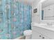 This bathroom features white vanity, toilet and a shower curtain with a seashell pattern at 5912 Village Cir # Ge, Orlando, FL 32822