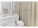 Bright bathroom with a framed mirror, white vanity, toilet, and a floral patterned shower curtain at 5912 Village Cir # Ge, Orlando, FL 32822