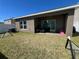 View of the home's back yard and exterior with white fencing, green grass, and covered patio at 939 Anna Pl, Davenport, FL 33837