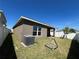 View of the home's back yard and exterior with white fencing, green grass, and covered patio at 939 Anna Pl, Davenport, FL 33837