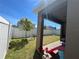View of the home's back yard with white fencing, green grass, and partially covered patio at 939 Anna Pl, Davenport, FL 33837