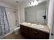 Bathroom featuring a double sink vanity, toilet, and shower/tub combo with a floral curtain at 939 Anna Pl, Davenport, FL 33837