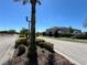 Community entrance featuring decorative landscaping, stone pillars, and a gate, set under a clear blue sky at 939 Anna Pl, Davenport, FL 33837