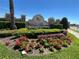 Landscaped entrance sign with flowers, greenery, and a stone structure under a clear blue sky at 939 Anna Pl, Davenport, FL 33837