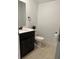 A powder room featuring a dark vanity, white sink, tan tile and decorative accents at 11713 Tidal Alley Trl, Orlando, FL 32832