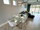 Modern dining area with a glass table, white chairs, and an adjacent living area with a dark sofa at 236 Villa Domani Cir, Davenport, FL 33896