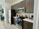 Well-equipped kitchen with stainless steel appliances, dark wood cabinets, and white countertops at 236 Villa Domani Cir, Davenport, FL 33896