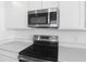 Close-up of stainless steel microwave and oven with white cabinets and countertops at 6389 Clover St, Lake Hamilton, FL 33851