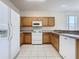 Well-lit kitchen with white appliances, wooden cabinets, and tile flooring at 205 Minniehaha Cir, Haines City, FL 33844