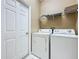Functional laundry room with white washer and dryer, shelving, and tile flooring at 205 Minniehaha Cir, Haines City, FL 33844