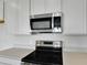 Close-up of stainless steel microwave and stove top with white cabinets and quartz countertops at 6393 Clover St, Lake Hamilton, FL 33851
