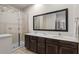 Bathroom featuring a glass-doored shower, a large mirror, and double sinks with dark cabinetry at 2618 Roadster Ln, Kissimmee, FL 34746