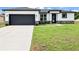 Charming single-story home boasts a modern design with a gray garage door and well-manicured lawn at 308 Miami Ln, Kissimmee, FL 34759