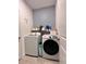 Laundry room with front loading washer and dryer, decorative wallpaper, and storage shelves at 9083 Coral Cape St, Kissimmee, FL 34747