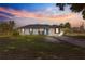 Beautiful single-story home features a modern front exterior with a manicured lawn under a colorful sunset at 1401 Nw 63Rd Pl, Ocala, FL 34475