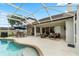 Screened-in pool area featuring an umbrella-covered dining set and comfortable outdoor seating at 3852 Brantley Place Cir, Apopka, FL 32703