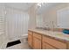 Well-lit bathroom features a granite countertop, wood cabinets, and shower with patterned curtain at 3852 Brantley Place Cir, Apopka, FL 32703