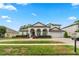 An elegant two-story home featuring a circular driveway, manicured landscaping, and arched entryways at 3852 Brantley Place Cir, Apopka, FL 32703