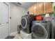 Laundry room with a gray washer and dryer, wooden cabinets, and a door to the outside at 3852 Brantley Place Cir, Apopka, FL 32703