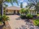Charming single-story home with a brick driveway, lush landscaping, and tropical palm trees at 107 Belzano Pl, Poinciana, FL 34759