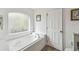 Bathroom featuring a white soaking tub with a window for natural light and a door for privacy at 1119 Mariner Cay Dr, Haines City, FL 33844