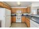 Efficient kitchen with oak cabinets, laminate counters, white appliances, and vinyl flooring at 1119 Mariner Cay Dr, Haines City, FL 33844