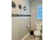 Neutral bathroom with wood-look flooring, decorative wall accents and a toilet at 1122 Spaceport Ct, Kissimmee, FL 34741
