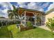 Backyard with a covered outdoor kitchen, BBQ area, garden beds and lush landscaping on a sunny day at 11242 Stone Gate Ct, Orlando, FL 32837