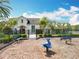 Community playground in front of model home featuring dolphin riders, benches, and manicured landscaping near a lake at 16588 Centipede St, Clermont, FL 34714