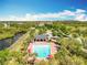 Aerial view of a community pool featuring lounge chairs, mature landscaping, and a neighborhood lake at 16588 Centipede St, Clermont, FL 34714