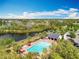 Aerial view of a community pool, surrounded by mature trees, lounge chairs, and a nearby lake at 16588 Centipede St, Clermont, FL 34714