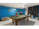 Spacious game room with a pool table, TV, and bright blue painted brick wall at 16621 Caribbean Breeze Way, Clermont, FL 34714