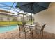 Relaxing outdoor patio featuring a table with umbrella and view of the screened pool at 16621 Caribbean Breeze Way, Clermont, FL 34714