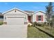 Charming single-story home featuring a front-entry garage, neat landscaping, and red front door and window shutters at 1737 Carnelian St, Deland, FL 32720