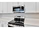 Modern kitchen with white cabinets, stainless steel microwave and range, and quartz countertop; stylish and functional at 1741 Carnelian St, Deland, FL 32720