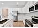 Well-lit kitchen with stainless steel appliances, white cabinets, quartz countertops, and wood-look flooring at 1741 Carnelian St, Deland, FL 32720