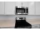 Close-up of the kitchen appliances, featuring a stainless steel microwave and electric cooktop at 1747 Carnelian St, Deland, FL 32720