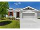 Charming single-Gathering home featuring a well-manicured lawn, gray exterior paint, and an attached two-car garage at 1749 Carnelian St, Deland, FL 32720