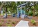 Community playground featuring climbing structures, slides, surrounded by lush trees and wood chip groundcover at 1749 Carnelian St, Deland, FL 32720