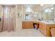Bathroom features a spacious vanity with dual sinks, bright lighting, and a shower with patterned curtains at 2322 Queenswood Cir, Kissimmee, FL 34743