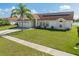 Charming single-story home featuring a well-manicured lawn, a palm tree, and solar panels for energy efficiency at 2322 Queenswood Cir, Kissimmee, FL 34743