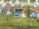 Aerial view of a home with solar panels and a screened-in pool, overlooking a serene backyard and lake at 2322 Queenswood Cir, Kissimmee, FL 34743
